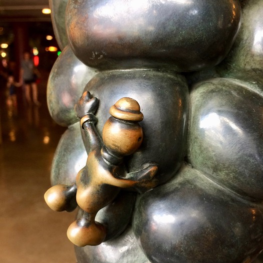 Sculpture of a little man clinging to bubble shaped metal