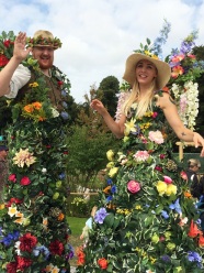 Man and lady on stilts in flower and leaf costumes