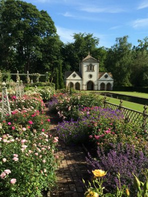 A folly behind a garden of roses and perennials