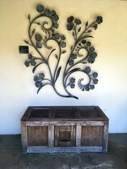 Flower scroll artwork above a rustic trunk at York Gate Garden